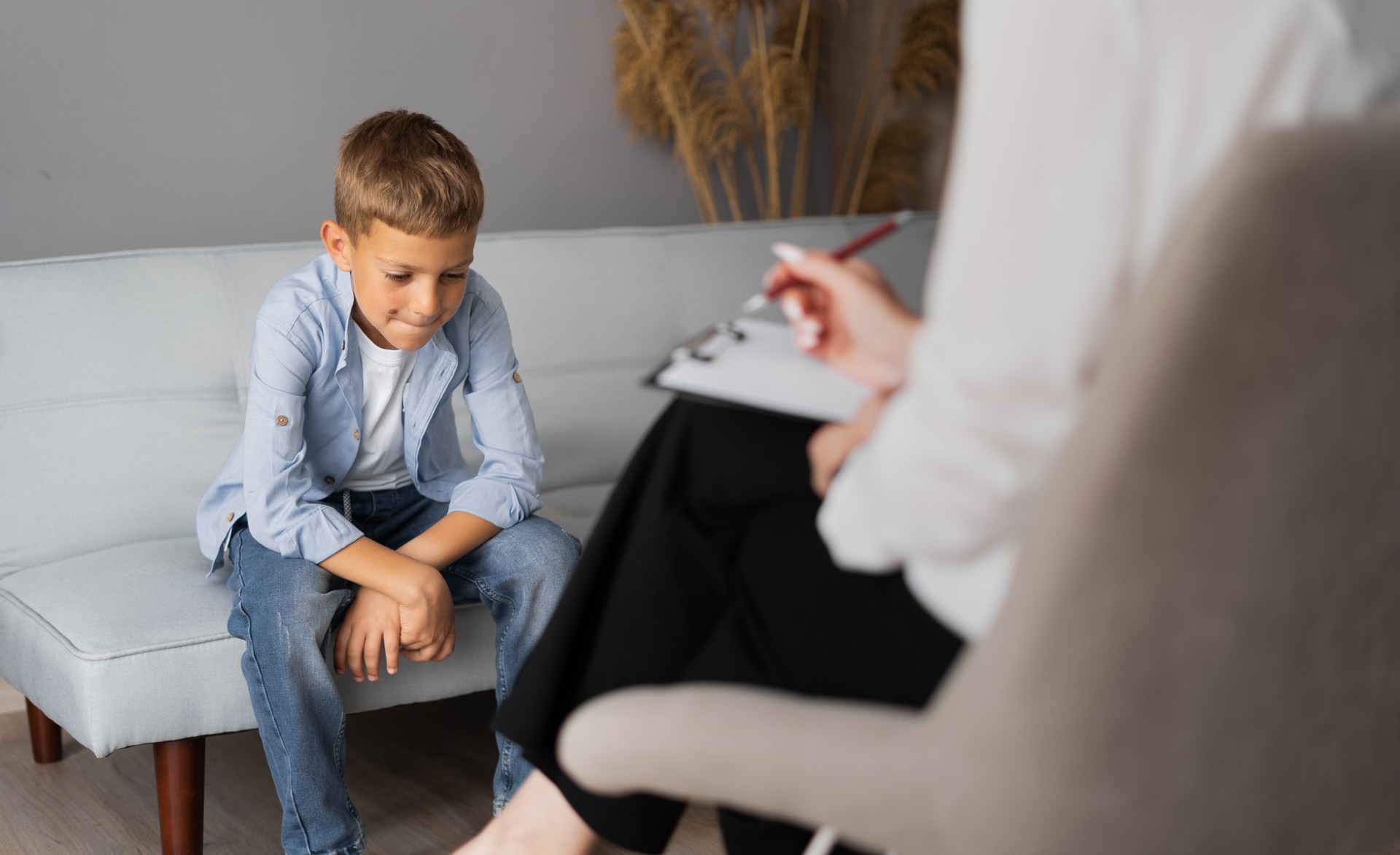 Professional child counsellor working with a schoolboy in a bright office. Children's mental therapy Professional child counsellor working with a schoolboy in a bright office. Children's mental therapy